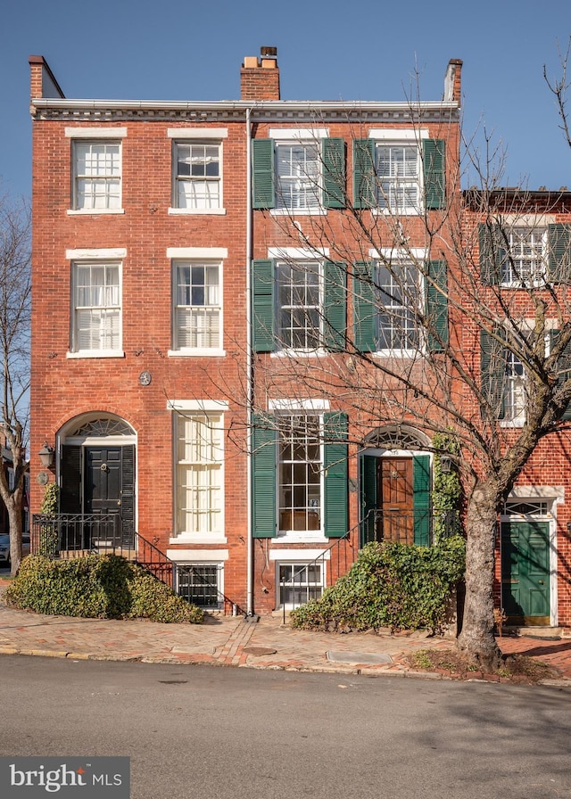 view of property featuring brick siding and a chimney