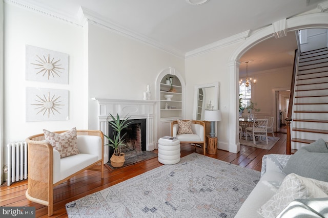 living area with radiator heating unit, arched walkways, wood-type flooring, and built in features