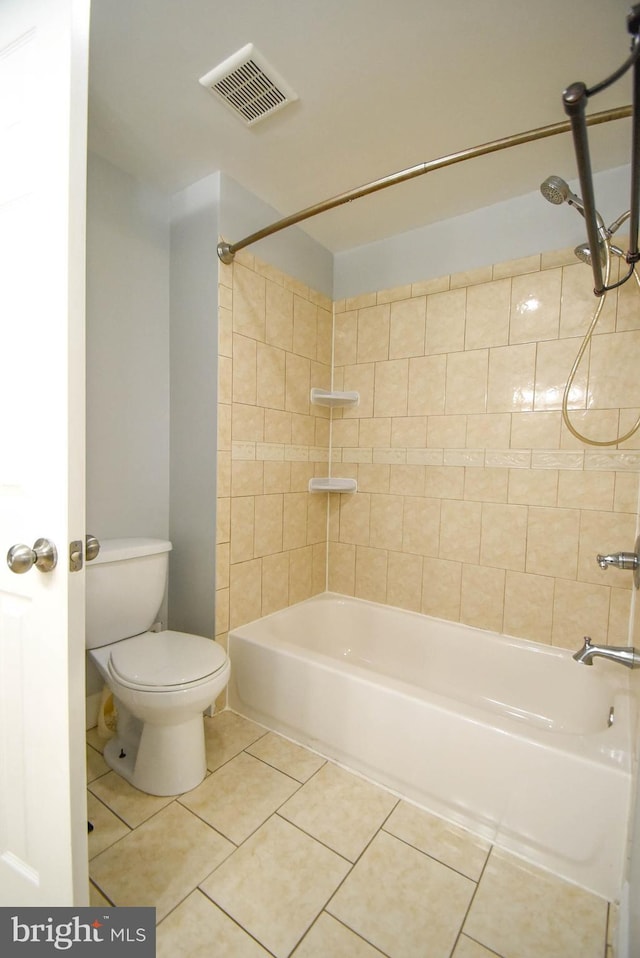 bathroom featuring tile patterned flooring, tiled shower / bath combo, and toilet