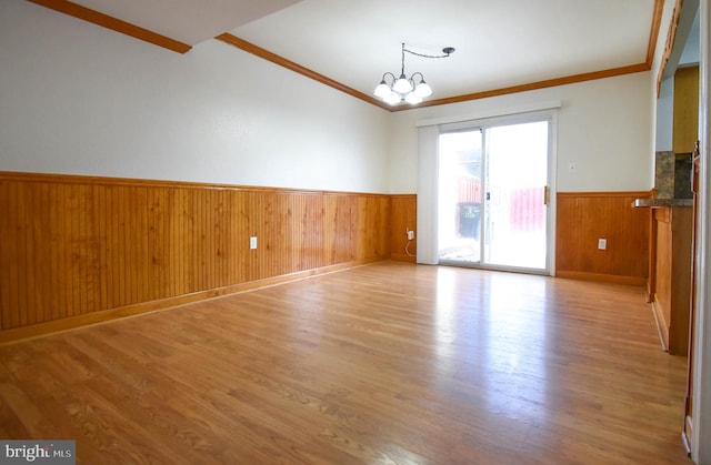 unfurnished room with a notable chandelier, crown molding, and light hardwood / wood-style floors