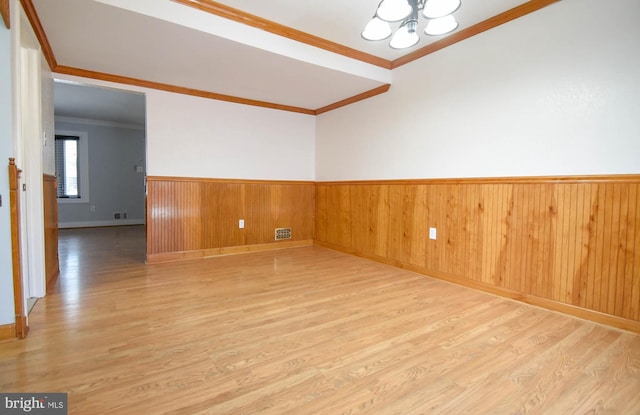 unfurnished room featuring ornamental molding, a notable chandelier, and light hardwood / wood-style flooring