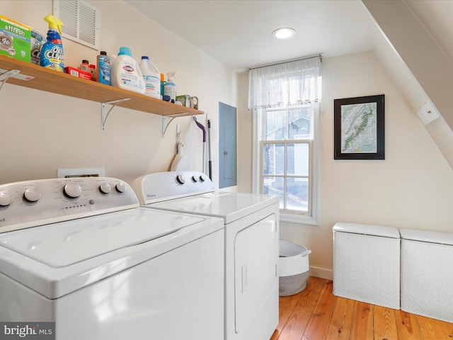 laundry area featuring a healthy amount of sunlight, electric panel, washer and dryer, and light hardwood / wood-style flooring