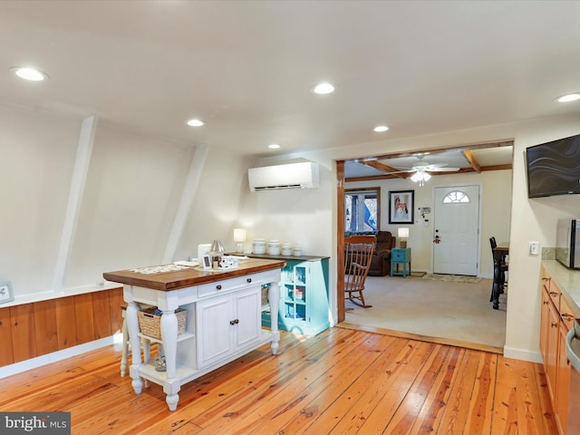 kitchen with butcher block counters, light hardwood / wood-style floors, an AC wall unit, and white cabinets