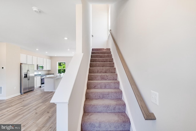 stairway with sink and hardwood / wood-style floors