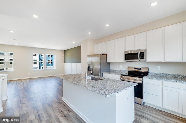 kitchen featuring sink, white cabinets, stainless steel appliances, and an island with sink