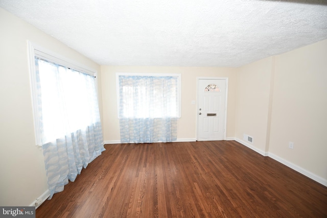 spare room with a textured ceiling and dark wood-type flooring