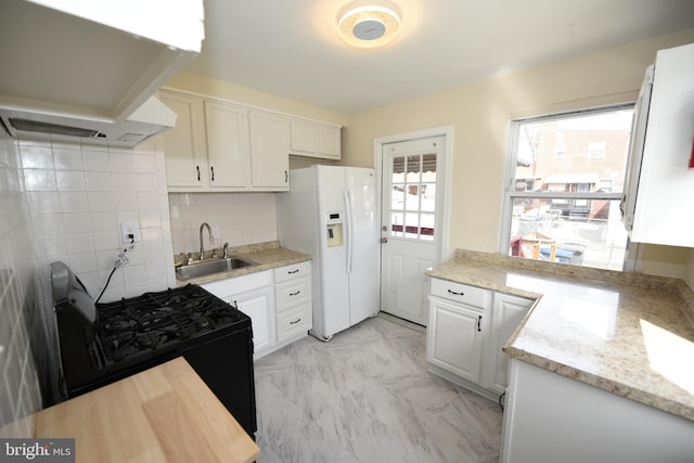 kitchen featuring white cabinets, white refrigerator with ice dispenser, sink, premium range hood, and black range with gas stovetop