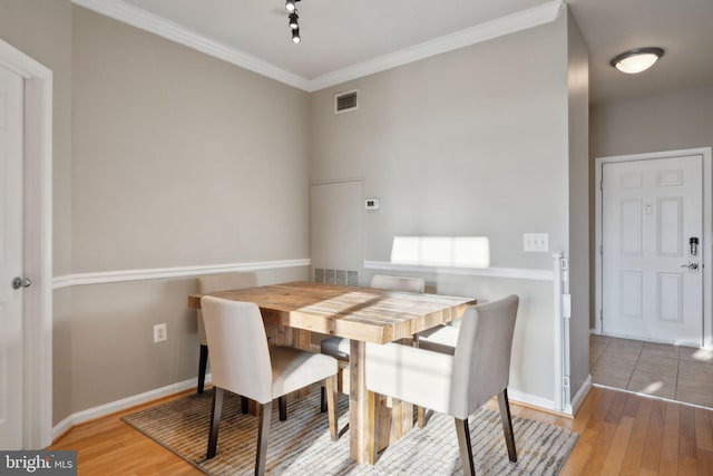 dining room with ornamental molding and light hardwood / wood-style flooring