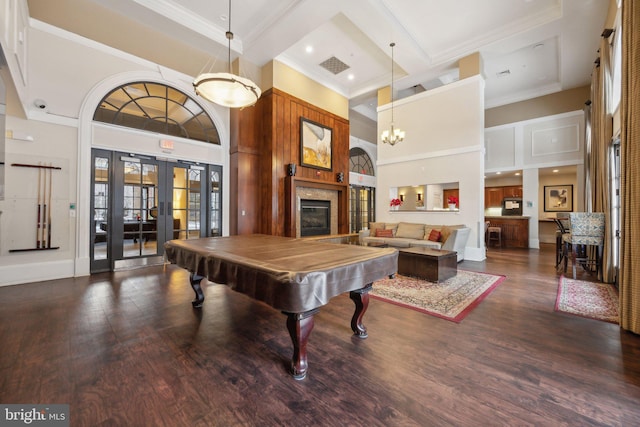 game room featuring ornamental molding, a towering ceiling, dark hardwood / wood-style flooring, and french doors