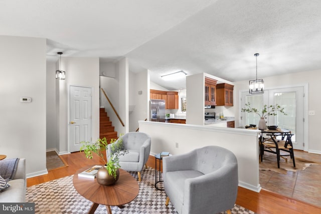 living room featuring vaulted ceiling, an inviting chandelier, and light wood-type flooring