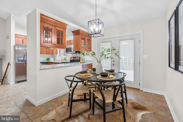 dining area with a textured ceiling, sink, and a notable chandelier