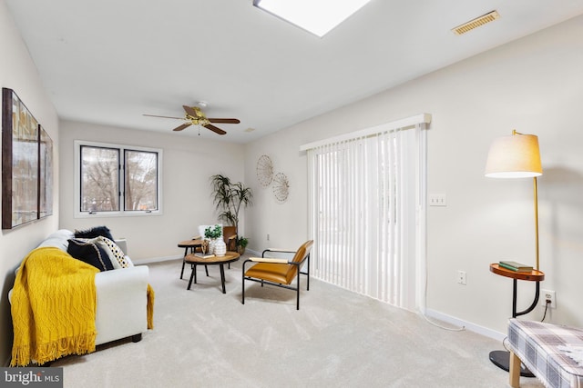 living area with ceiling fan and light carpet