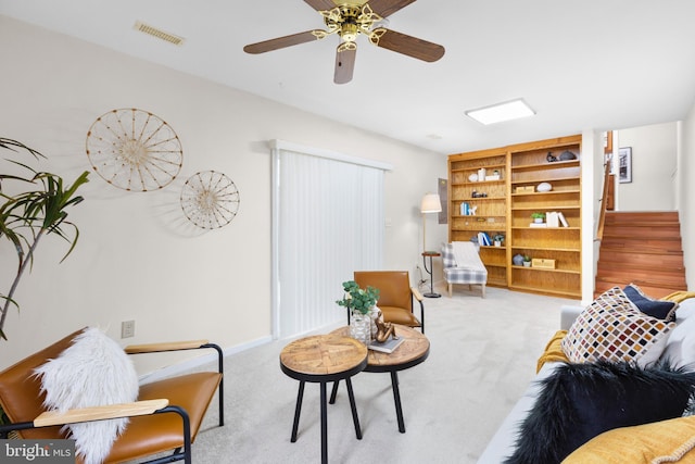 living room with ceiling fan, built in shelves, and light carpet