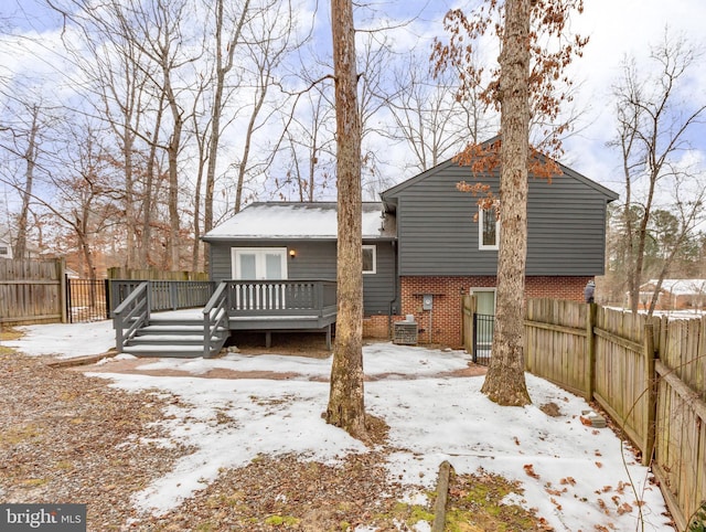 snow covered back of property with a deck