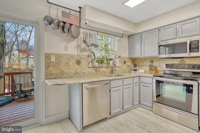 kitchen featuring sink, light stone counters, appliances with stainless steel finishes, and plenty of natural light