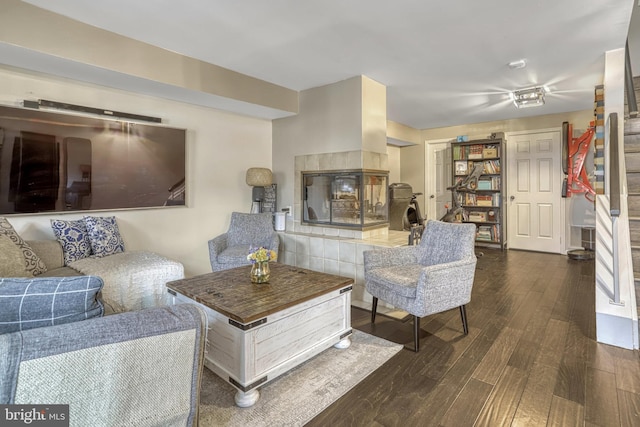 living room featuring dark wood-type flooring and a tiled fireplace