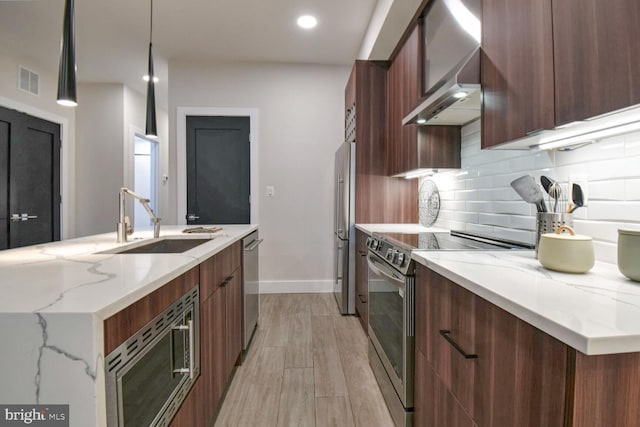 kitchen featuring appliances with stainless steel finishes, pendant lighting, sink, decorative backsplash, and light stone counters