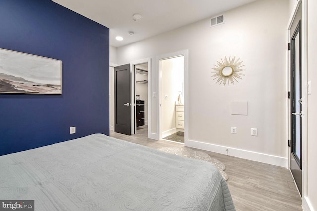 unfurnished bedroom featuring a walk in closet, light hardwood / wood-style floors, a closet, and ensuite bathroom