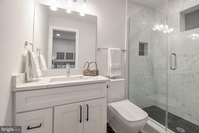 bathroom with toilet, vanity, and a shower with shower door