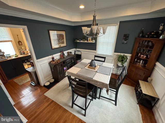 dining space featuring crown molding, hardwood / wood-style floors, and a notable chandelier