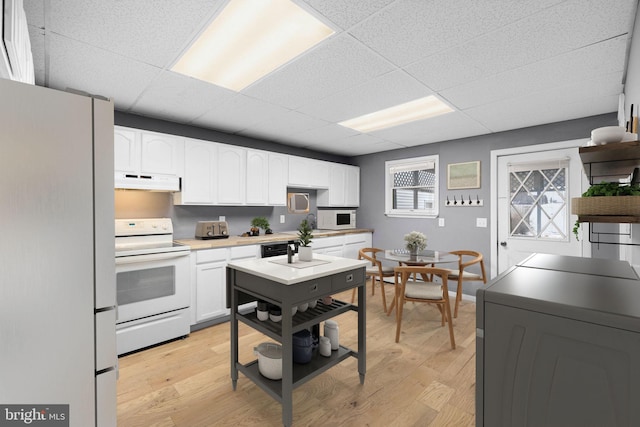 kitchen featuring white cabinetry, light hardwood / wood-style floors, white appliances, a drop ceiling, and washer / clothes dryer