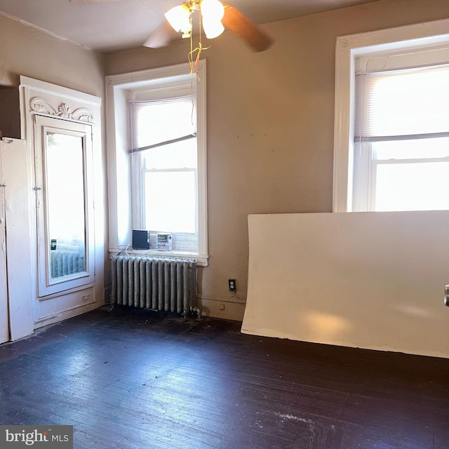 empty room with dark hardwood / wood-style flooring and radiator