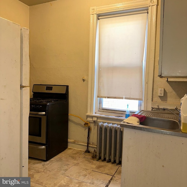 kitchen with radiator heating unit, sink, and stainless steel gas range oven