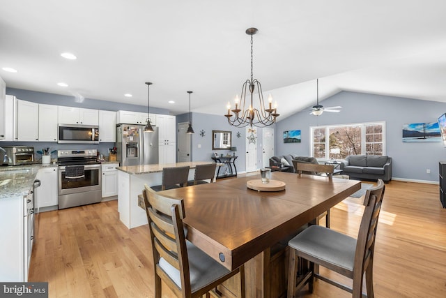 dining room with lofted ceiling, sink, ceiling fan with notable chandelier, and light hardwood / wood-style flooring