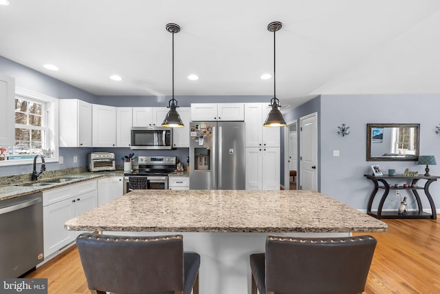 kitchen featuring a center island, appliances with stainless steel finishes, light stone counters, and pendant lighting