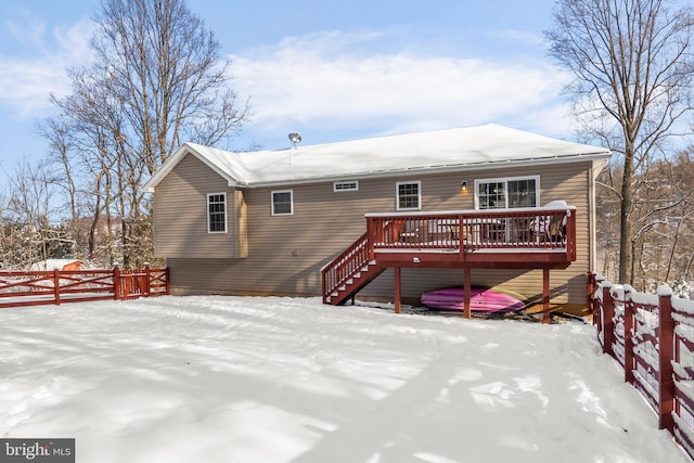 snow covered back of property with a deck