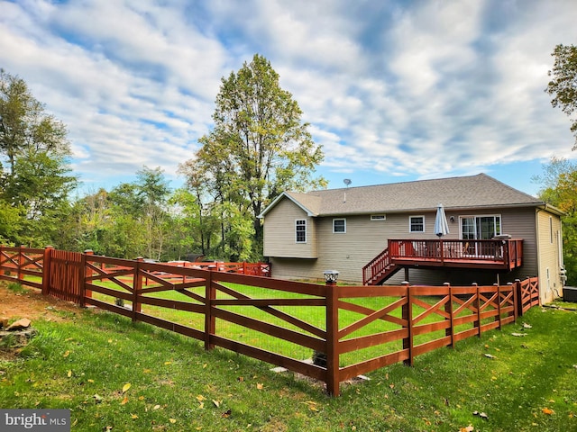 rear view of property featuring a yard and a wooden deck