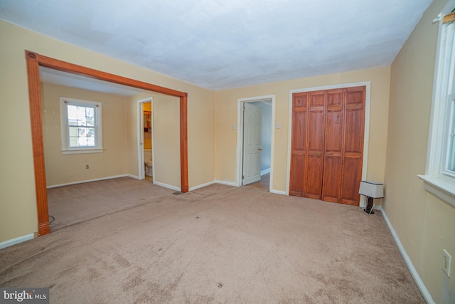 unfurnished bedroom with light carpet and connected bathroom