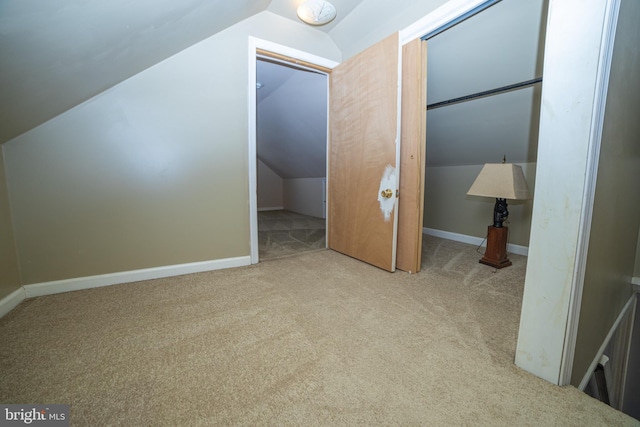 bonus room with lofted ceiling and light colored carpet