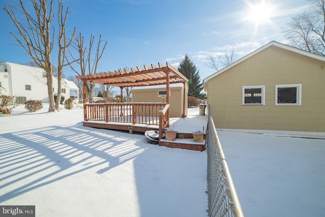 snow covered house featuring a wooden deck and a pergola