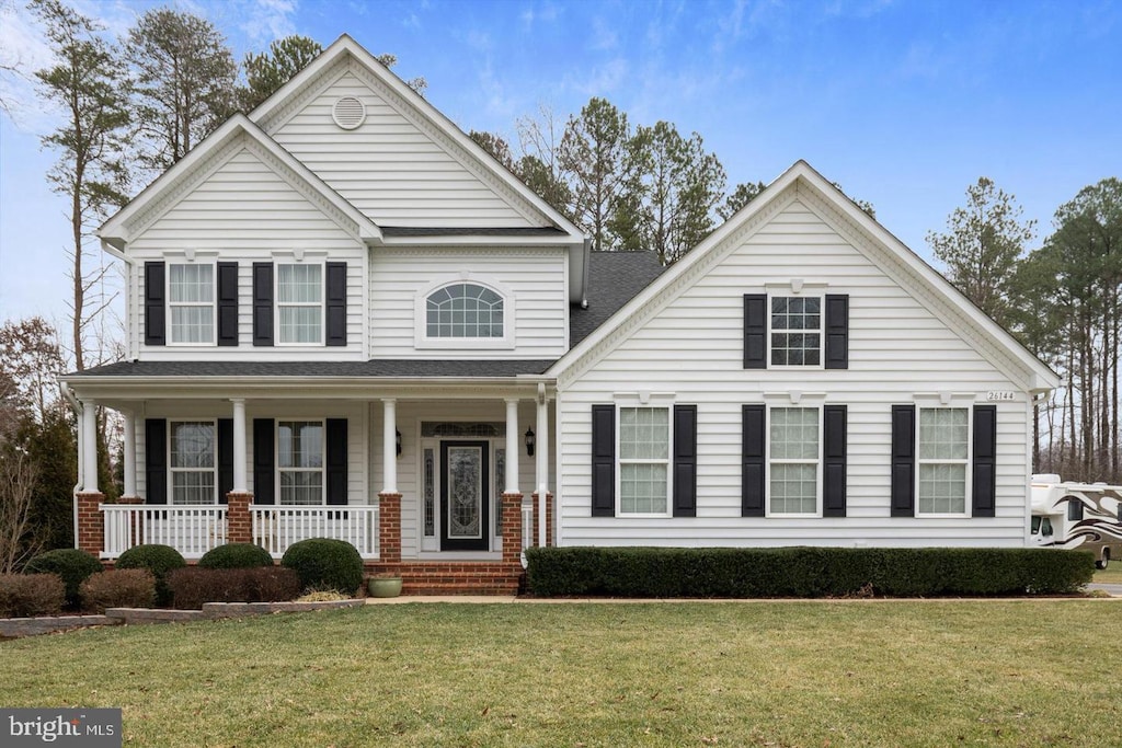 front facade featuring covered porch and a front lawn