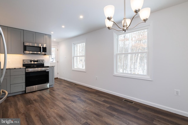 kitchen featuring light stone counters, backsplash, gray cabinets, and appliances with stainless steel finishes