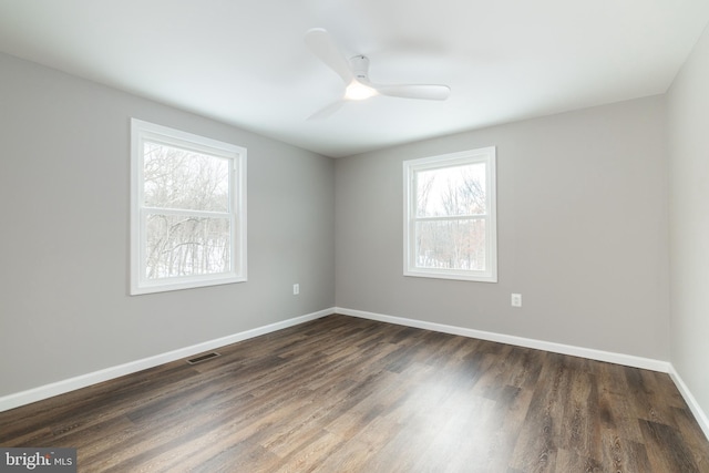 empty room with ceiling fan, plenty of natural light, and dark hardwood / wood-style flooring