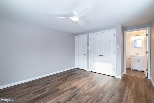 unfurnished bedroom featuring ensuite bathroom, dark wood-type flooring, and ceiling fan