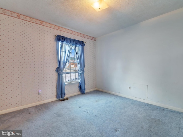 carpeted empty room featuring a textured ceiling