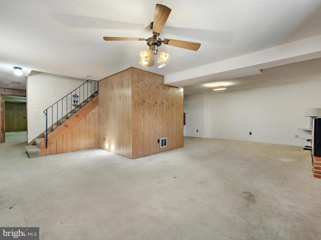 unfurnished living room with light carpet, wooden walls, and a textured ceiling