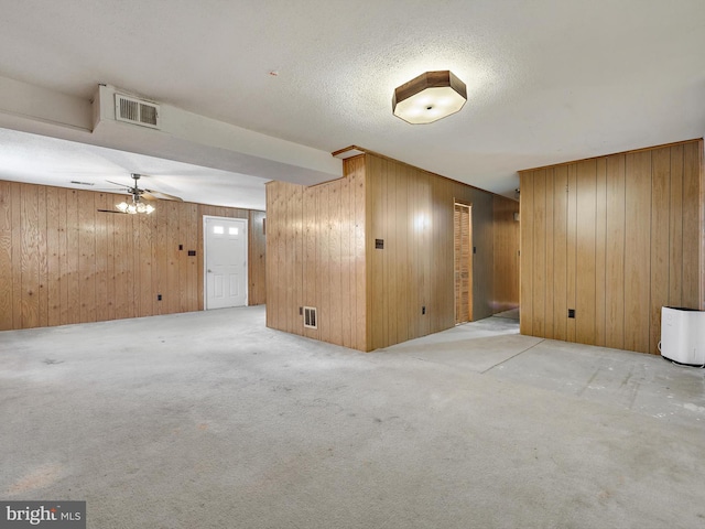 interior space featuring ceiling fan, light colored carpet, and wood walls