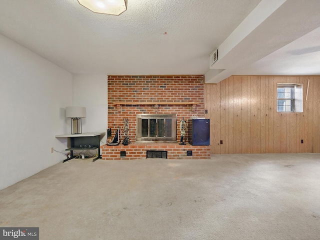 unfurnished living room with carpet, a fireplace, wood walls, and a textured ceiling