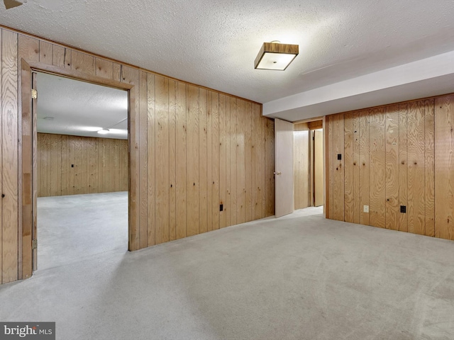 basement with light colored carpet, a textured ceiling, and wood walls