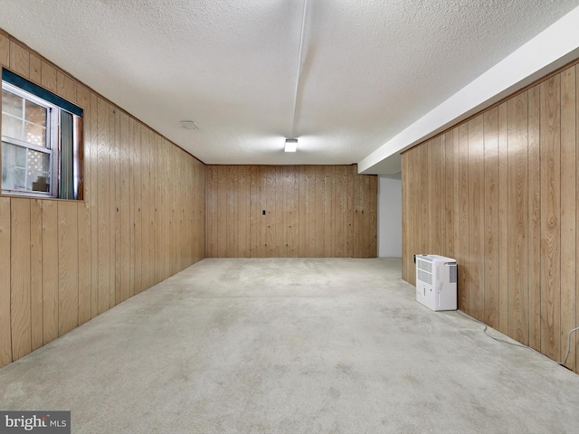 basement with light colored carpet, wooden walls, and a textured ceiling