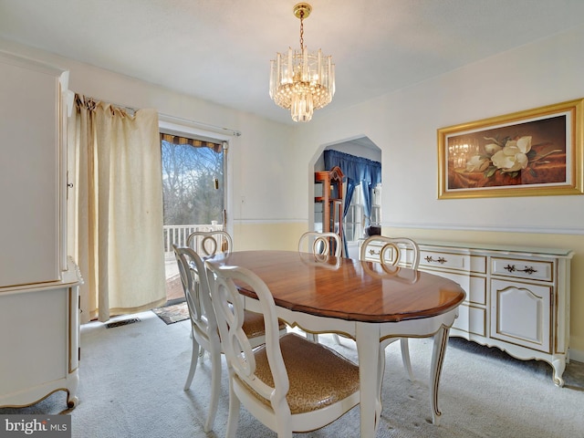 carpeted dining area with a notable chandelier