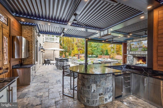 view of patio with an outdoor stone fireplace and a bar