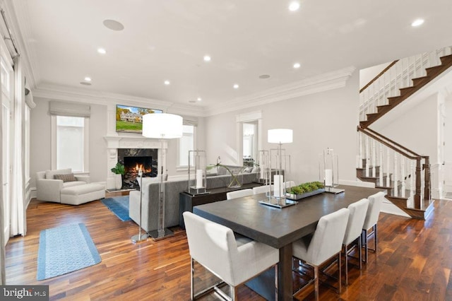 dining room with dark wood-type flooring, a high end fireplace, and crown molding