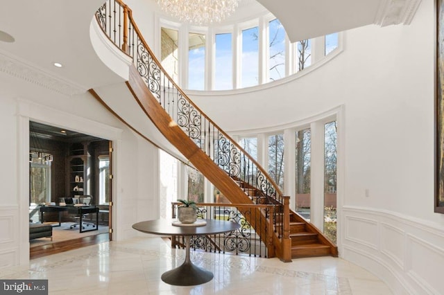 staircase featuring a high ceiling, a chandelier, and ornamental molding