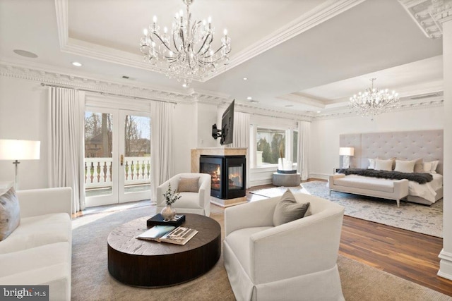 living room featuring a multi sided fireplace, crown molding, hardwood / wood-style flooring, and a tray ceiling