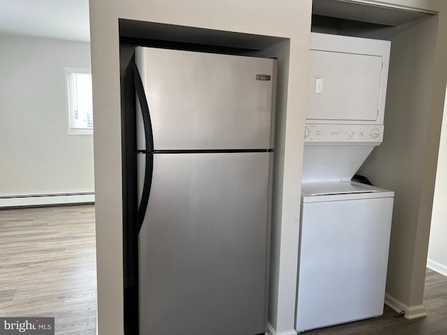 laundry room featuring light wood-type flooring, stacked washer / dryer, and a baseboard heating unit